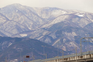 高速道路と雪化粧の山 冬の自然と交通の風景
