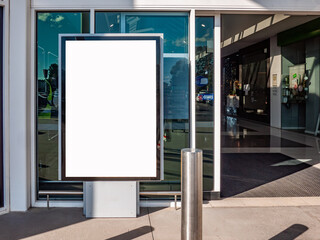 A blank white advertising mockup billboard display stand positioned at the entrance of a retail store or shopping mall to attract customers entering. Copy space for design.