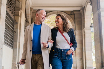 Cheerful couple enjoying a leisurely stroll together while holding hands, radiating happiness and affection in a charming urban environment, sharing a good moments together