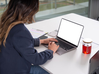 Businesswoman using laptop mock up, over shoulder view young caucasian brunette long hair businesswoman using laptop mock up typing looking empty blank screen sitting office desk copy space. 