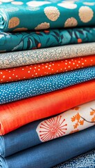 A stack of colorful fabric bolts showcases various patterns and textures, teal, orange and white tones.
