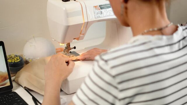 Fashion artisan carefully aligns fabric under sewing machine, maintaining accuracy in stitching. Passion for detail and precision defines handmade fashion industry. Sewing tools, pins, seam ripper