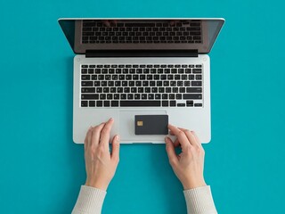 A person is holding a credit card near an open laptop computer