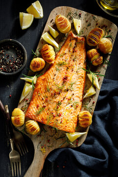 Roast salmon fillet seasoned with lemon zest and herbs  with hasselback potatoes, top view