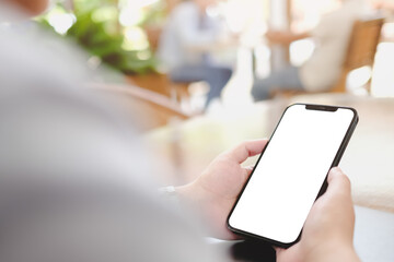 Close-up of a smartphone with blank screen in a bright, leafy cafe setting, emphasizing mobile usage.