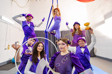 Group of circus performers wearing purple costumes showing their skills, posing together in their...