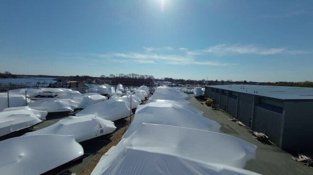 Boats that are covered in white shrink wrap for winter storage or protection. Porter River Danvers Massachusetts.