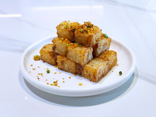 asian deep fried crispy vegetable carrot cake in square w garlic onion spices in plate on marble...