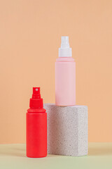 Cosmetic pink bottle. Womens cosmetic accessory for makeup with stylish props on cream background.