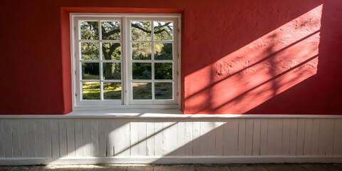 Window with shadow on the wall in a red house, sunny day