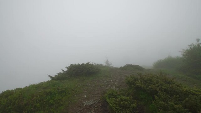Walking by mountain ridge trail inside the deep mist with first person view
