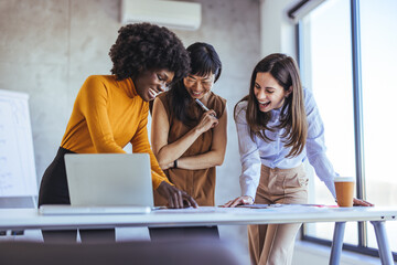 Professional Women Collaborating and Laughing During a Business Meeting in Modern Office