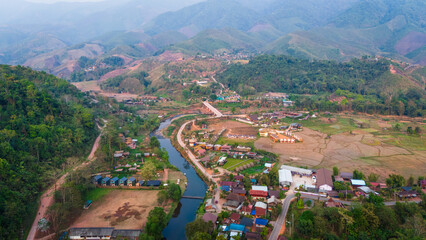 Fototapeta premium Aerial view of Sapan Village in Mueang Nan District, a hidden gem in Thailand rice field and river in mountains landscape