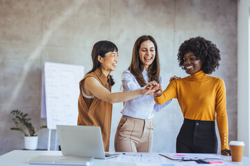 Three Professional Women Celebrating Teamwork and Success in a Modern Office Setting