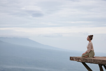 Meditation in the mountains, a girl sits on a platform in the mountains, Bali Indonesia landscape