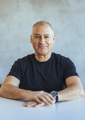 Smiling Mature Man Sitting at Table in a Bright Room