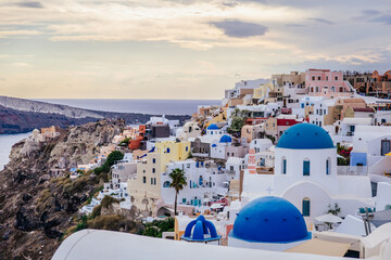 Scenic view of Oia, Santorini, Greece, with blue-domed churches, colorful houses, and the Aegean Sea. Horizontal shot with a cloudy sky, a beautiful island travel, honeymoon or wedding destination