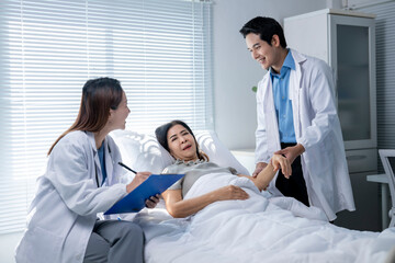 Fototapeta premium A woman is laying in a hospital bed with two doctors standing over her