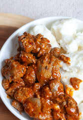 A bowl of South African street food, spicy chicken livers with traditional pap