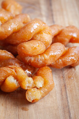 A close up of a plate of traditional South African Koeksisters with a wooden table underneath