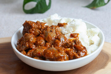 A bowl of South African street food, spicy chicken livers with traditional pap