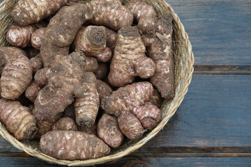 wicker basket with jerusalem artichoke harvest on wooden background. superfood topinambur