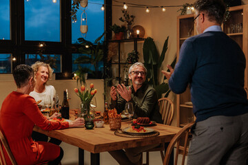 Senior man giving speech during retirement dinner with friends
