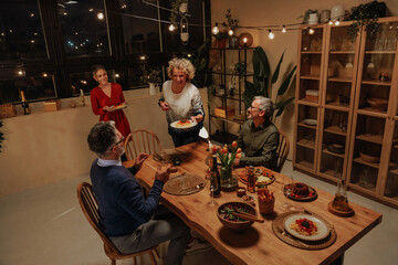 Family celebrating together at home enjoying dinner party with string lights