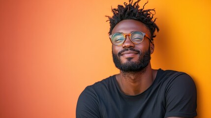 A confident man with glasses poses against a vibrant orange wall, radiating positivity and self-assuredness, creating a striking and energetic visual impact.