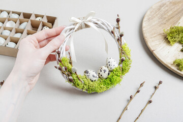 Florist at work: woman shows how to make traditional Easter door wreath with moss, quail eggs and catkins. Step by step, tutorial.