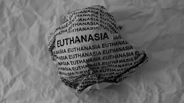 Crumpled paper ball with words Euthanasia on a crumpled white paper background.
