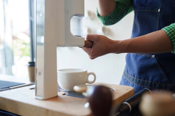 Sustainable Innovation and Coffee Preparation. A barista uses modern equipment to craft coffee, focusing on sustainable methods.