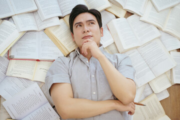 Student deep in thought surrounded by open books while studying in a cozy indoor space