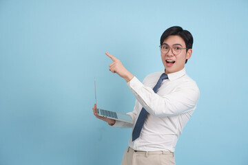 Young professional excitedly pointing at an idea while holding a laptop in a bright blue background