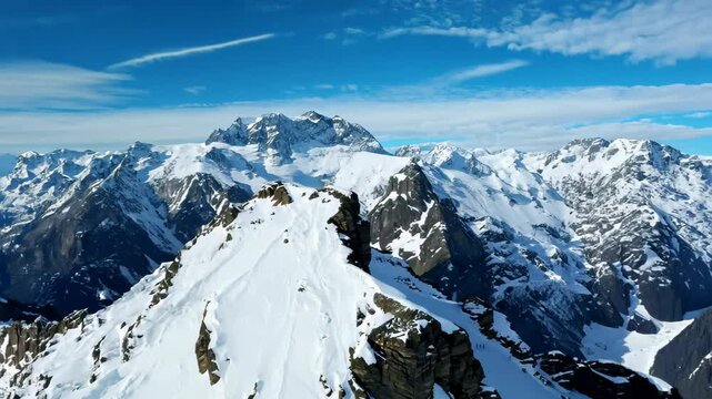 Aerial Drone Flight Over Snowy Mountain Summit Under Bright Sun in Liechtenstein