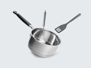 Saucepan, slotted spatula and whisk in air on white background