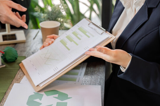 Data Analysis and Environmental Impact. A businesswoman reviewing sustainability reports, focusing on ecological data in professional settings.