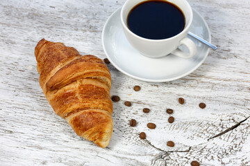 kruvasan cup of coffee and croissant on a rustic white wooden	
