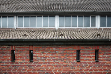 A symmetrical view of a red brick building featuring narrow vertical windows and a tiled roof.