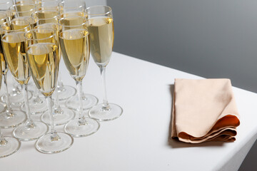 Glasses filled with champagne on a table with a white tablecloth and a pink salfette