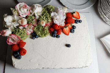 White square cake with fresh flowers and berries