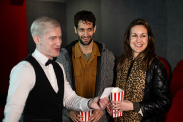 Usher checking tickets of couple entering movie theater with popcorn