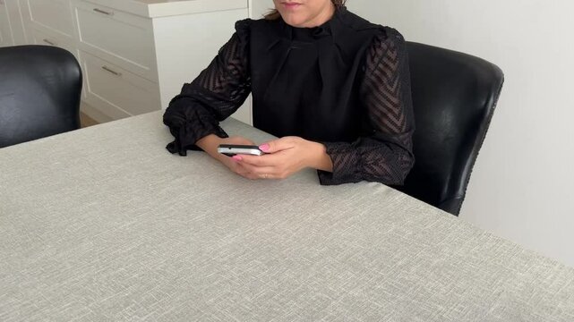 Mulher faz comunica&ccedil;&atilde;o com celular trabalhando em casa 