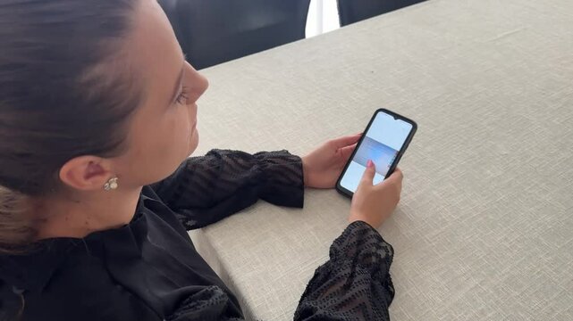 Mulher faz comunica&ccedil;&atilde;o com celular trabalhando em casa 