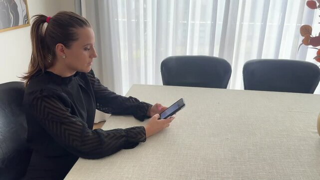 Mulher faz comunica&ccedil;&atilde;o com celular trabalhando em casa 
