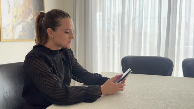 Mulher faz comunica&ccedil;&atilde;o com celular trabalhando em casa 