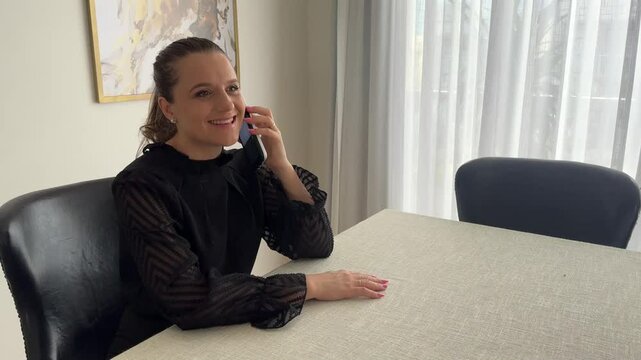 Mulher faz comunica&ccedil;&atilde;o com celular trabalhando em casa 