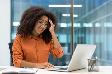 Upset frustrated woman working with laptop inside office. Businesswoman unsatisfied reading online email notification message from laptop