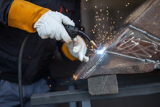 Welder joining metal parts with welding torch creating sparks