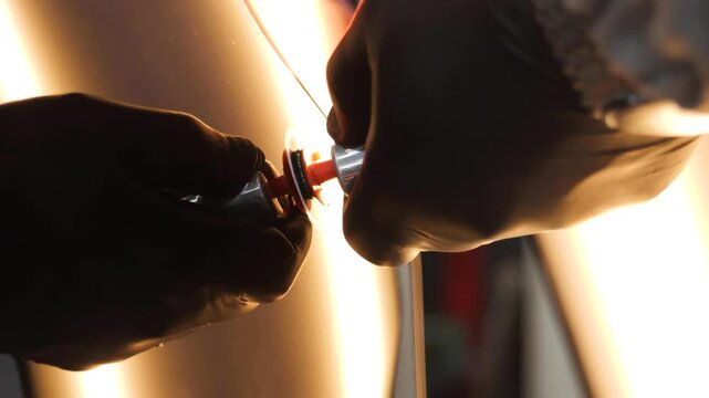 Hands preparing PDR tool: Close-up of gloved hands attaching a tab for paintless dent repair, emphasizing automotive skill and precision work